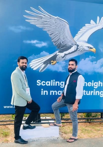 Shriprasad team beside a 'Scaling new heights in manufacturing' billboard